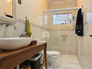 Foto de um banheiro com box de vidro e revestimento cerâmico.