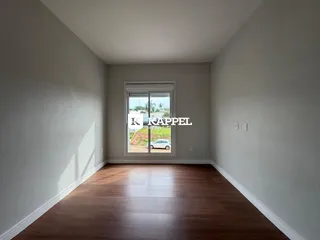 Uma sala de estar com piso de madeira e uma grande janela.