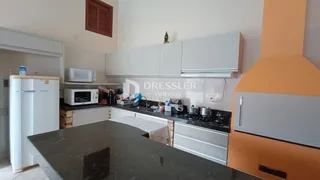 Foto de uma cozinha com armários brancos e bancadas escuras.