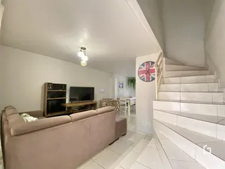 Sala de estar com sofá e escadaria em ambiente claro.