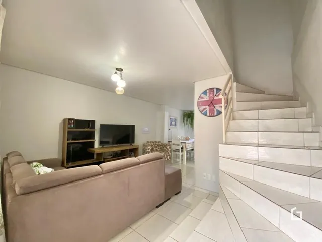 Sala de estar com sofá e escadaria em ambiente claro.