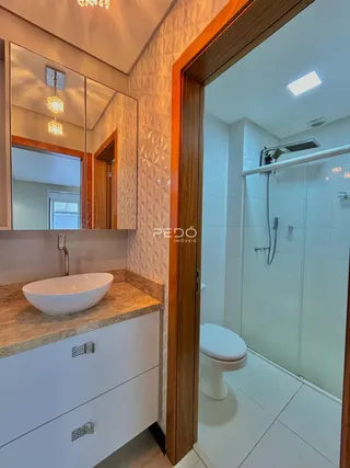 Vista de um banheiro com bancada e box de vidro em uma residência.