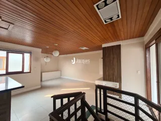 Interior de uma sala de estar com teto de madeira e piso de cerâmica.