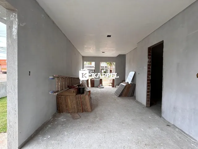 Foto de um corredor interno em uma área em construção com paredes de gesso e materiais de obra.