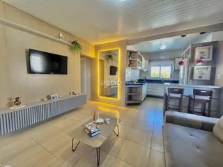 Sala de estar com piso de cerâmica e televisão na parede de uma residência.