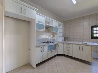 Cozinha com armários brancos e piso claro.