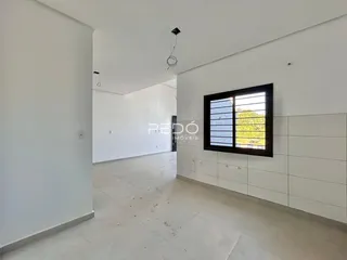 Interior de uma sala ampla com paredes brancas e piso claro.