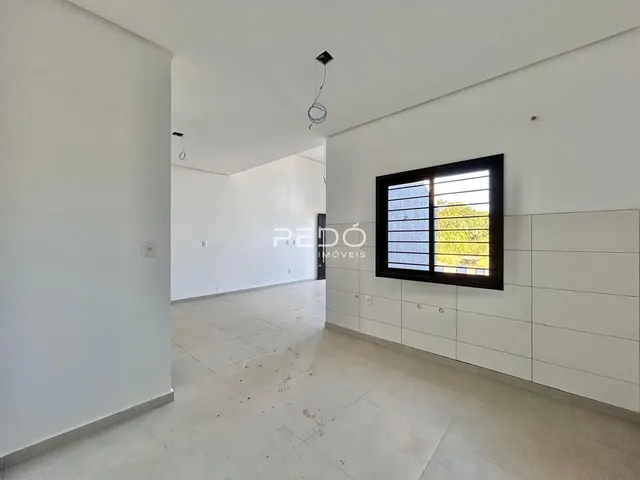 Interior de uma sala ampla com paredes brancas e piso claro.