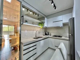 Cozinha moderna com armários brancos e bancadas claras.