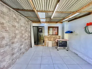 Vista interna de um ambiente com piso de cerâmica e teto de metal ondulado.