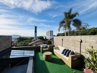 Vista de uma varanda com mobiliário externo e paisagem urbana.