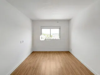 Foto de um cômodo interno com piso de madeira clara e uma janela.