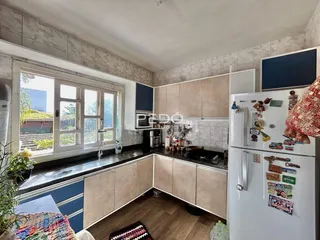 Ambiente interno de sala de estar com cozinha e vista para o exterior.