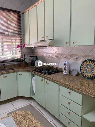 Esta é uma foto de uma cozinha com armários verdes e bancada de granito.