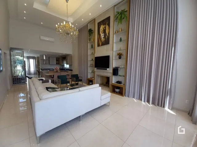 Sala de estar moderna com sofá branco e janelas com cortinas brancas.