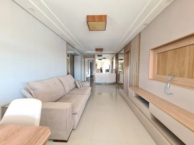 Sala de estar com um sofá claro e piso claro.