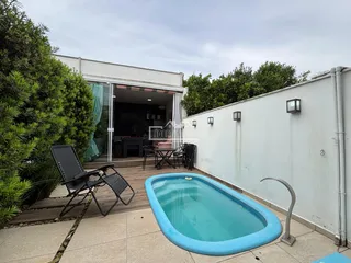 Foto da área externa com piscina e deck de madeira.