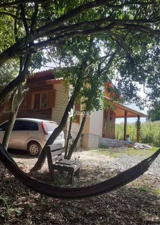 Vista externa de uma propriedade com árvores e um banco no jardim.