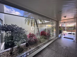 Vista de um ambiente interno com grandes janelas de vidro que dão para um jardim.