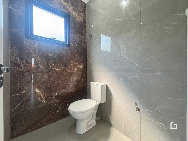 Foto de um banheiro com paredes de mármore e piso claro.