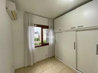 Quarto com armários embutidos e piso de cerâmica claro.