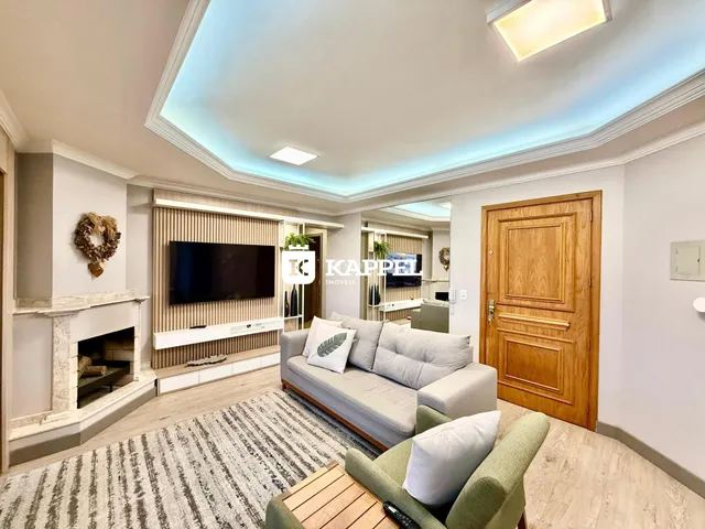 Sala de estar com sofá, televisão e lareira em ambiente interno.