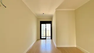 Corredor interno de uma residência com piso de madeira clara.
