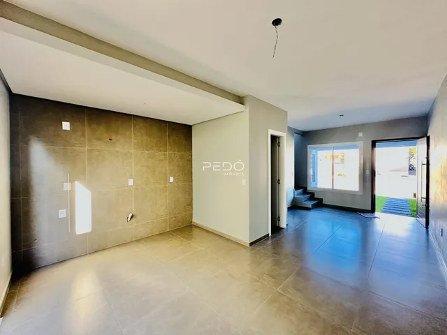 Ambiente interno de uma sala ampla com piso de cerâmica e paredes texturizadas.