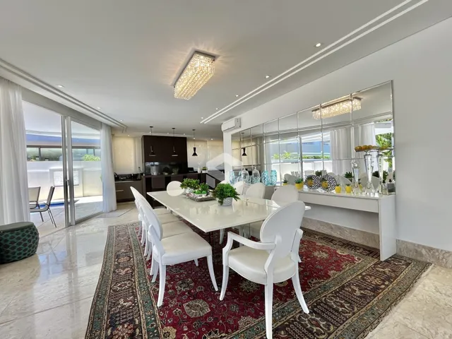 Uma sala de jantar ampla com mesa e cadeiras brancas em um ambiente iluminado.