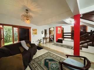 Sala de estar com vista para a natureza e escadaria interna.