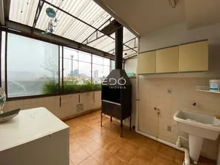 Vista interna de uma cozinha com janela grande e teto de telhado metálico.