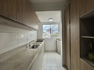 Cozinha moderna com armários de madeira e bancadas claras.