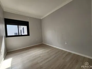 Ambiente interno com piso de madeira clara e janela.