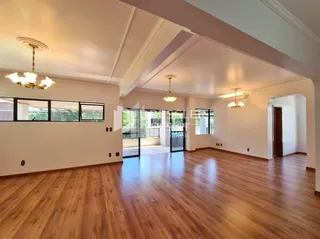 Sala de estar com piso de madeira e molduras brancas.