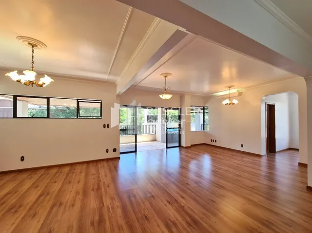 Sala de estar com piso de madeira e molduras brancas.
