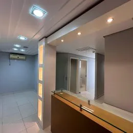 Hall de entrada com paredes brancas e iluminação clara.