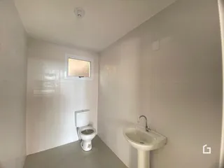 Foto de um banheiro interno com azulejos brancos e louças sanitárias.