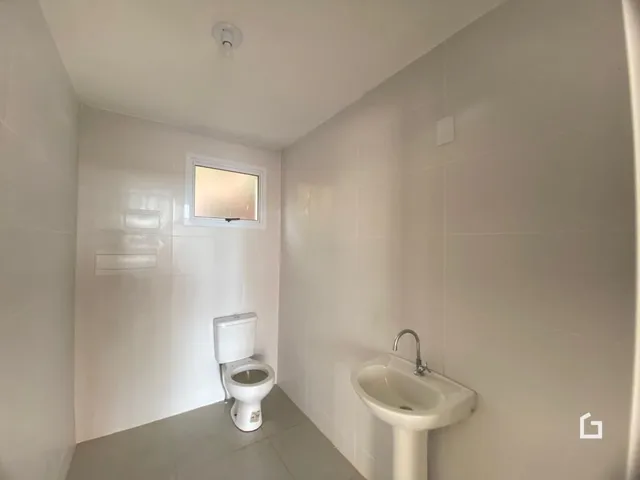 Foto de um banheiro interno com azulejos brancos e louças sanitárias.
