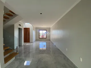 Hall de entrada longo com piso de concreto e escadaria de madeira.