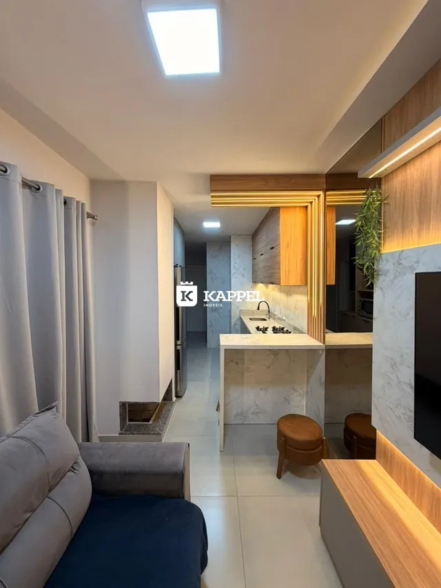 Uma sala de estar moderna com sofá e detalhes em madeira clara.