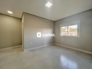 Esta é uma foto de um ambiente interno amplo com paredes claras e uma janela grande.