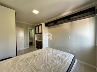Quarto com cama e piso de madeira clara.