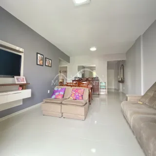 Sala de estar com sofá e televisão em um ambiente claro e amplo.