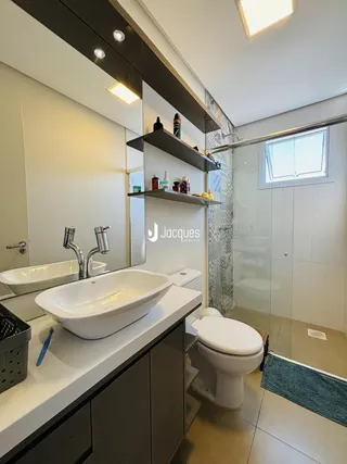 Banheiro moderno com bancada dupla e box de vidro.
