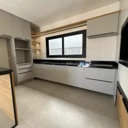 Foto interna de uma cozinha com armários brancos e bancada escura.