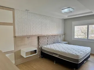 Quarto com cabeceira estofada e parede texturizada em um imóvel no Brasil.