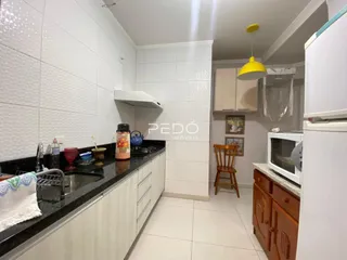 Foto de uma cozinha com armários brancos e bancadas escuras.