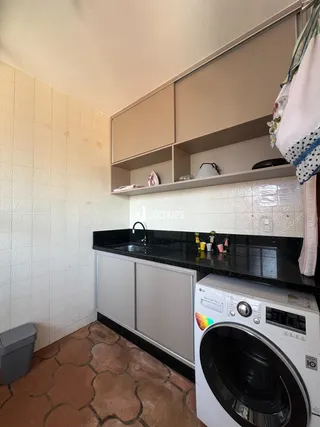 Uma cozinha com revestimento de cerâmica branca e bancada escura.