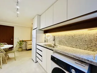 Vista da cozinha moderna com armários brancos e bancada de granito.