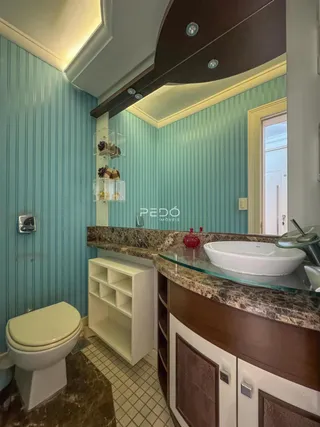 Interior de um banheiro com revestimento azul claro e bancada de mármore.